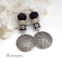 These handcrafted sterling silver earrings have an ethnic, tribal vibe. They feature African carved bone, glass and batik bone beads accented with hand stamped sterling silver dangles. Bold and striking, they'll make an exotic statement. Perfect for women that love to wear unique jewelry. Handmade in the USA by Silver and Earth Jewelry. 