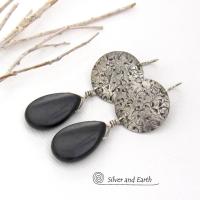 These handcrafted sterling silver earrings have a hand stamped texture and feature dangling black onyx teardrop-shaped gemstones. They have a contemporary modern style with a bold urban chic flair that coordinates beautifully with all wardrobe types.