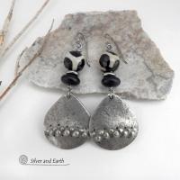 These handcrafted silver pewter earrings have a rustic, hammered texture and are accented with black and off-white Tibetan agate faceted gemstones, black glass and stainless steel beads. Bold and striking, they'll make a unique ethnic tribal statement. Perfect for women that love to wear unique, eye-catching jewelry. Handmade in the USA by Silver and Earth Jewelry.  MEASUREMENTS: Total length of approximately 2-1/2" from top of silver niobium (hypoallergenic) ear wires and 1” at widest point.