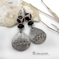 These handcrafted silver pewter earrings have a rustic, hammered texture and are accented with black and off-white Tibetan agate faceted gemstones, black glass and stainless steel beads. Bold and striking, they'll make a unique ethnic tribal statement. Perfect for women that love to wear unique, eye-catching jewelry. Handmade in the USA by Silver and Earth Jewelry.  MEASUREMENTS: Total length of approximately 2-1/2" from top of silver niobium (hypoallergenic) ear wires and 1” at widest point.