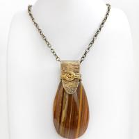 This handcrafted necklace features a natural brown tiger's eye gemstone accented with a gold brass bail. The stone has a beautiful matrix with earthy hues of brown and golden streaks. It has an earthy, modern style that coordinates beautifully with all wardrobe types. Unique and one of a kind, it makes a great gift for a natural stone lover - or a nice addition to your own jewelry collection.