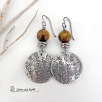 The earrings are handmade and are a beautiful example of nature-inspired jewelry. They feature solid pewter round discs with a hand stamped leaf design and are accented with brown tiger's eye gemstones and stainless steel beads.They showcase a beautiful hand stamped texture accented with high-quality natural gemstones and will make a great gift for a nature lover. Handmade by artist Silver and Earth, a New Mexico True Certified business. 