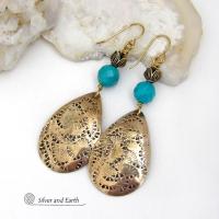 These handcrafted gold brass teardrop dangle earrings have a hand stamped texture accented with natural turquoise gemstones with a faceted finish and tulip flower-shaped brass beads. Big, long and striking - they have a modern elegant boho chic style that makes a bold statement. They'll coordinate beautifully with all wardrobe types - dressed up or down. Handmade in the USA by Silver and Earth Jewelry. 