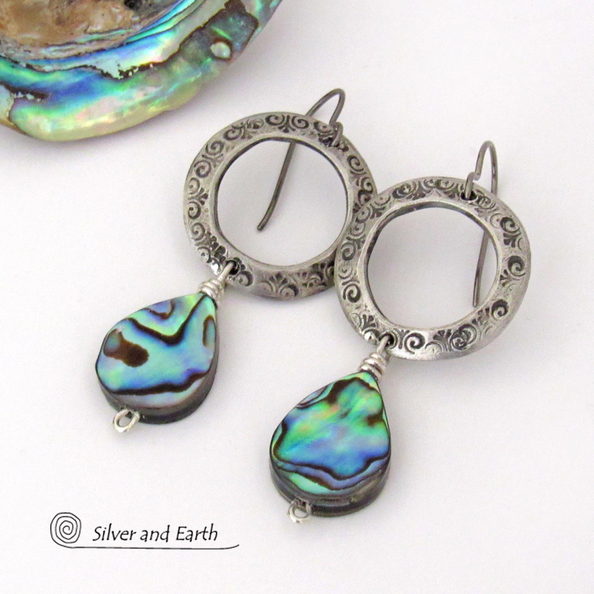 Vibrant natural abalone shells dangle from handcrafted silver pewter hoops in these modern stylish earrings. Each shell has its own unique pattern - with beautiful swirls and streaks of peacock blue, green, purple, silver and charcoal and a lovely iridescent shine. Lightweight and comfortable to wear, they'll look great with all wardrobe styles. 