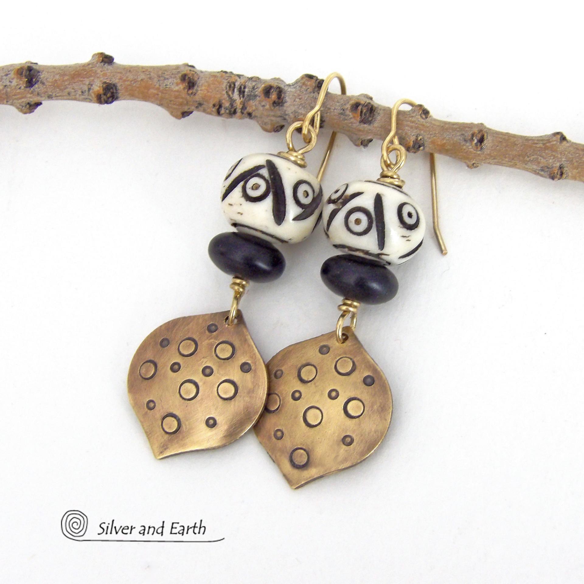 These handcrafted gold brass earrings have an ethnic, boho tribal vibe that makes a unique bold statement. They feature brass drops with a hand stamped texture accented with African carved bone beads with a bold pattern of dots and lines and matte black glass beads. Perfect for women that love unique handmade jewelry. Handmade in the USA by Silver and Earth Jewelry.