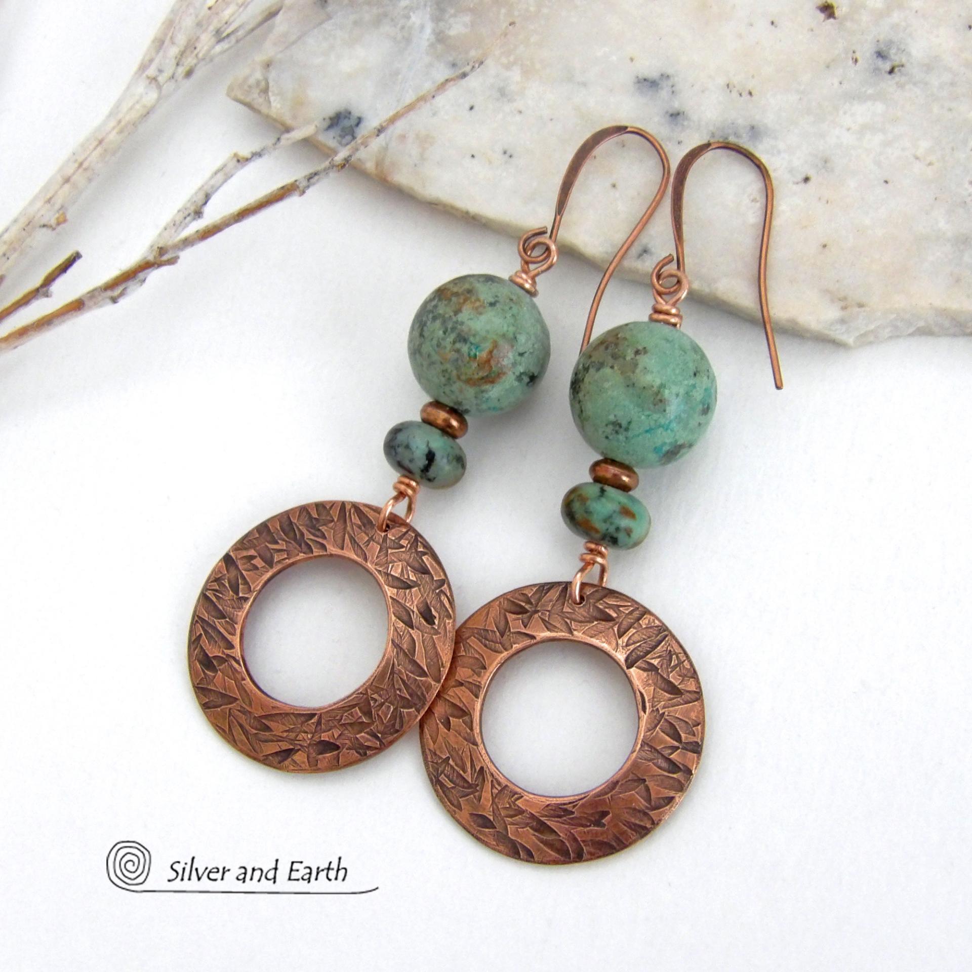  These handcrafted earrings feature round copper hoop dangles with a hand stamped texture accented with a stack of natural African turquoise stones and tiny copper beads. The stones have a pretty turquoise hue with an earthy natural black and brown matrix. These earrings have an earthy chic style with a modern bohemian flair that will coordinate beautifully with all wardrobe types. Handmade in the USA by Silver and Earth Jewelry.  Your choice of ear wires - copper or hypoallergenic niobium. 