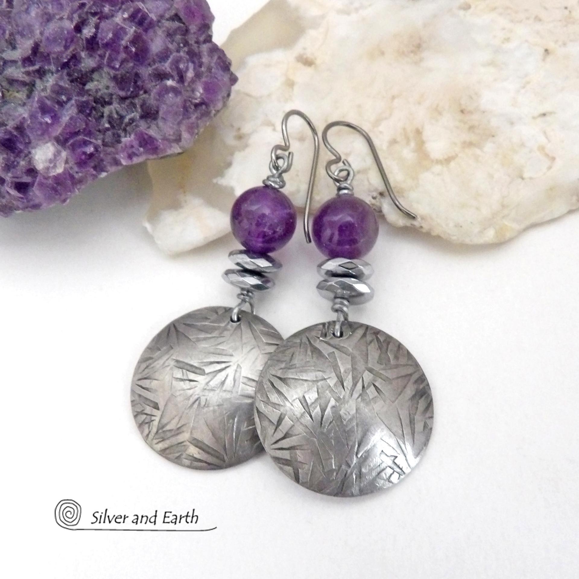 These handcrafted round silver pewter earrings have a hand stamped texture and are accented with purple amethyst and faceted hematite gemstones. The hematite has a natural sparkle and shine which gives these earrings an elegant, modern chic style that will look great dressed up or down. They'll coordinate beautifully with all wardrobe styles. Makes a great gift for someone with a February birthday - amethyst is that month's birthstone. Handmade in the USA by Silver and Earth Jewelry.