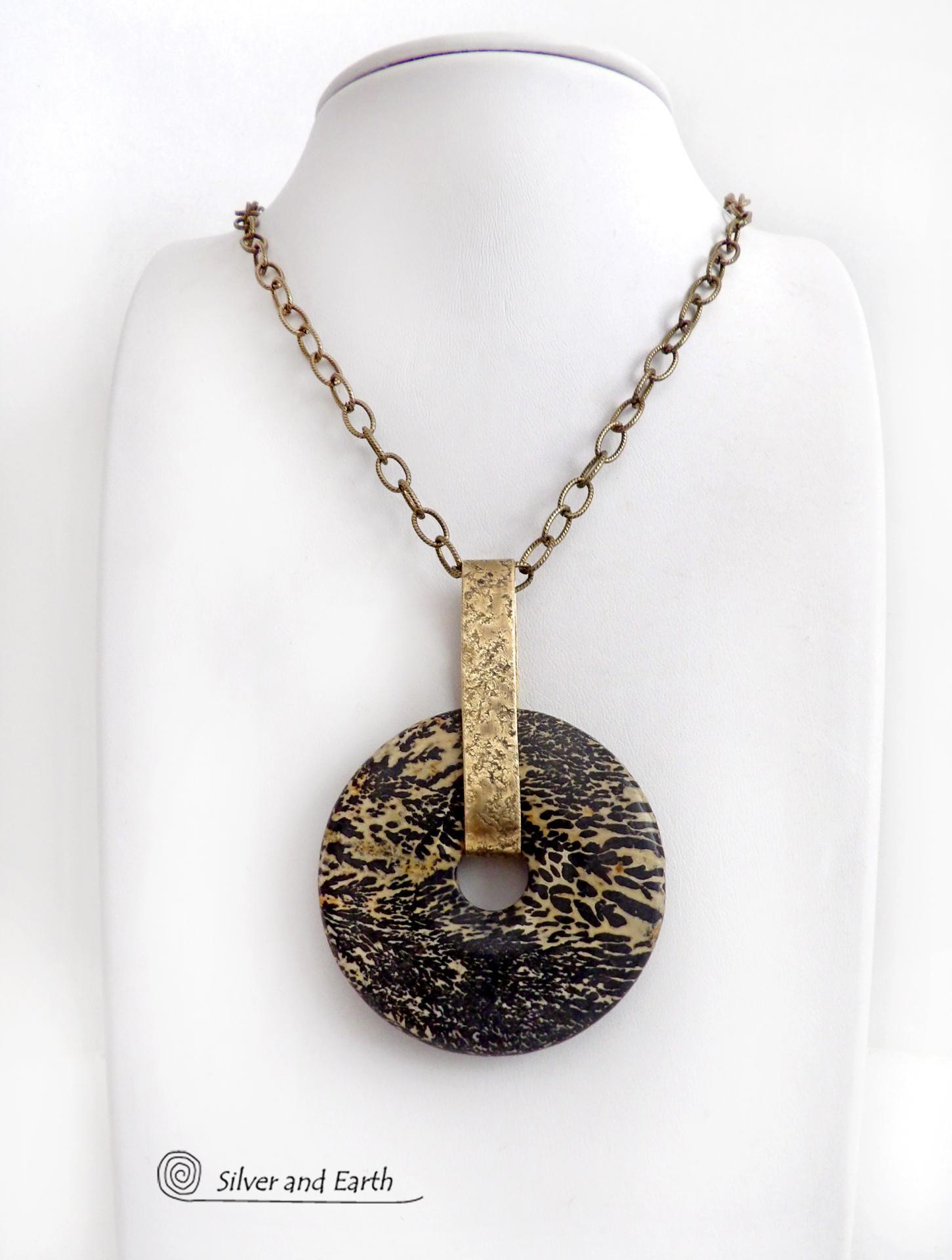 This one-of-a-kind pendant necklace features a stunning artistic jasper stone accented with a hand forged gold brass bail. This type of jasper is known for its intricate, natural patterns that resemble brushstrokes, landscapes, or abstract art. The stone in this piece has a natural bold dramatic pattern in hues of black and soft golden yellow with black streaks that resemble "feathery" dendrites. The design is modern and bold - yet classic and always in fashion. It can be worn by either a man or women. 