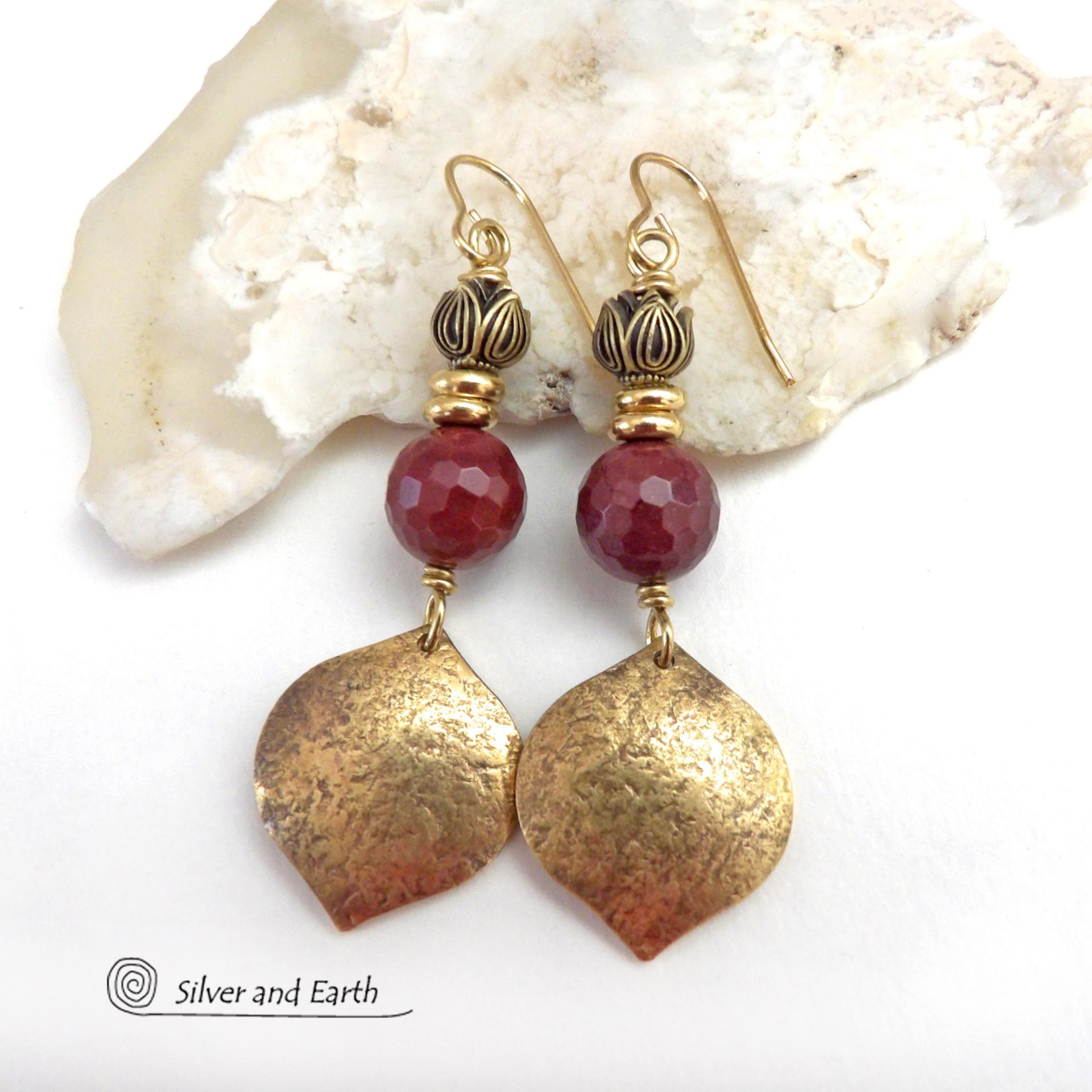 These handcrafted gold brass earrings have a hammered raw silk texture and are accented with micro-faceted burgundy mookaite gemstones, tiny brass beads and tulip flower-shaped beads. Mookaite is a unique, colorful type of jasper that is found at the Mooka Creek in Western Australia. It's known for distinct colors of burgundy, yellows, pinks, and purples. These earrings have a modern elegant chic style that coordinates beautifully with all wardrobe types. Handmade in the USA by Silver and Earth Jewelry. 