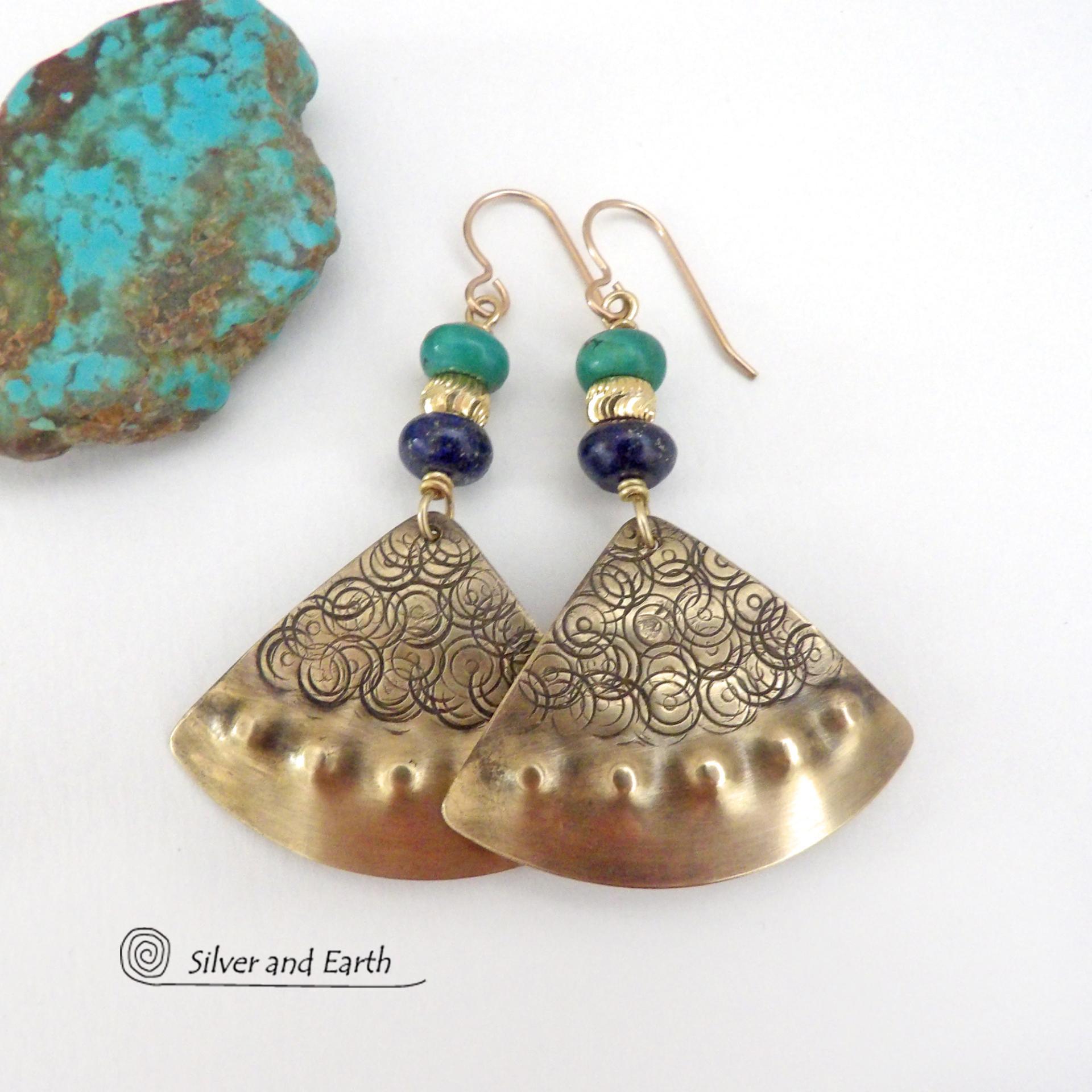 These handcrafted gold brass earrings have an exotic, Egyptian inspired vibe. The design consists of brass fan-shaped dangles with a hand textured design accented with lapis lazuli and turquoise gemstones and gold plated beads. Bold and unique, they'll add a touch of cultural exotic charm to any type of wardrobe. Handmade in the USA by Silver and Earth Jewelry, these earrings are a beautiful and stylish way to add a touch of elegance to any outfit. 