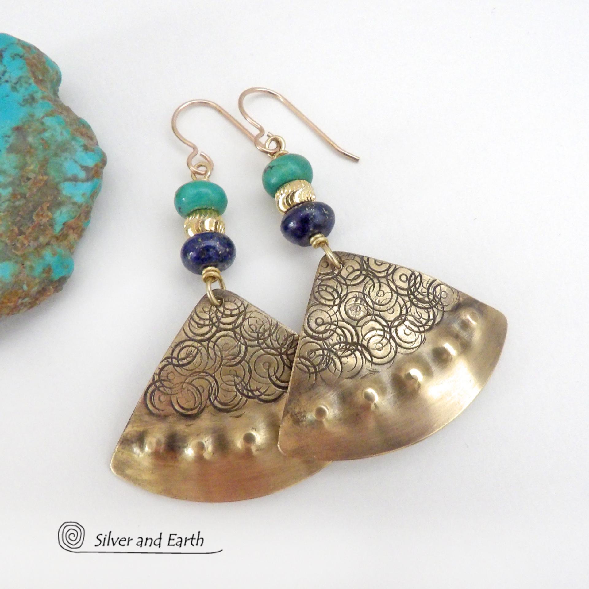 These handcrafted gold brass earrings have an exotic, Egyptian inspired vibe. The design consists of brass fan-shaped dangles with a hand textured design accented with lapis lazuli and turquoise gemstones and gold plated beads. Bold and unique, they'll add a touch of cultural exotic charm to any type of wardrobe. Handmade in the USA by Silver and Earth Jewelry, these earrings are a beautiful and stylish way to add a touch of elegance to any outfit. 