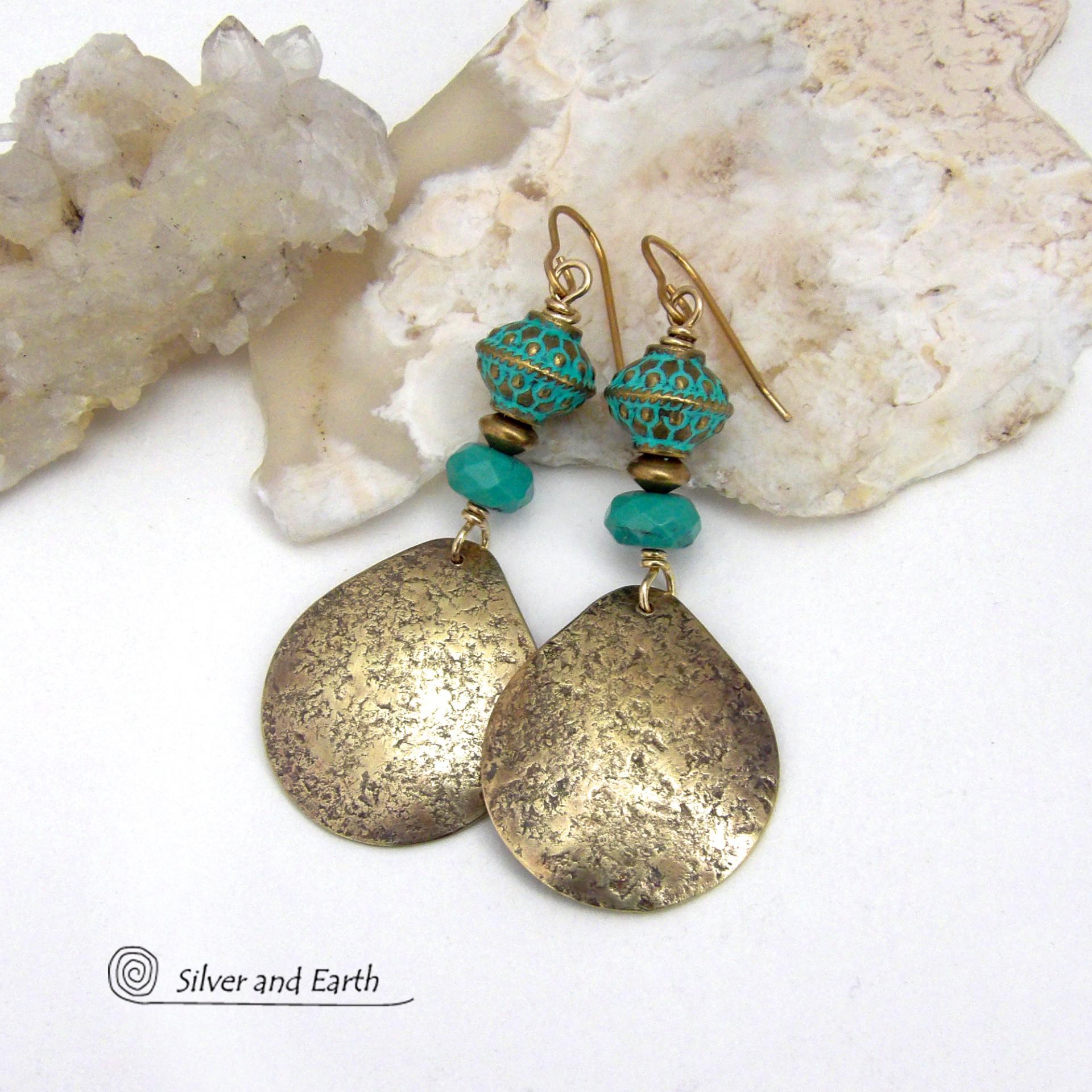 These handcrafted earrings have an elegant modern style with a tribal boho chic flair. They feature gold brass dangles with a hammered organic silky texture accented with faceted genuine turquoise gemstones, tiny brass beads and blue-green patina beads with a tribal style pattern. Bold and unique, they'll make a striking statement. Handmade in the USA by Silver and Earth Jewelry.