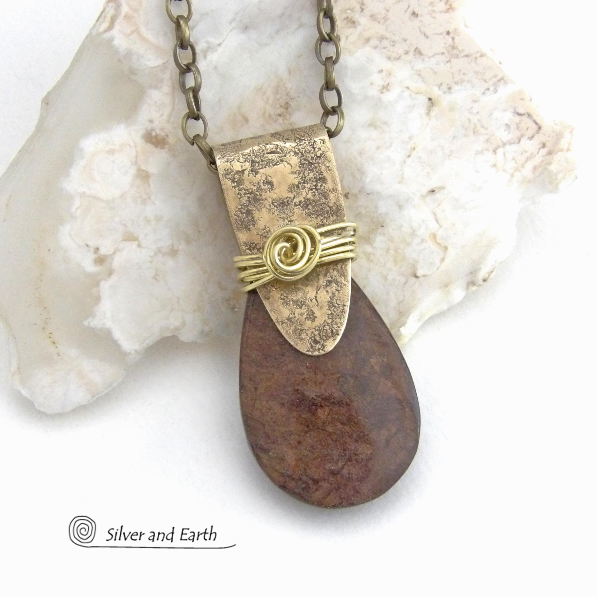 This handcrafted necklace features a natural bronzite gemstone accented with a gold brass bail. The stone has a beautiful chocolate brown hue with a subtle golden shimmer. Bronzite is a mineral that shares characteristics with rock that is found in meteorites, such as iron. It's this blend of several minerals which gives bronzite its unique mottled characteristic. The necklace has an earthy, modern style that coordinates beautifully with all wardrobe types. 