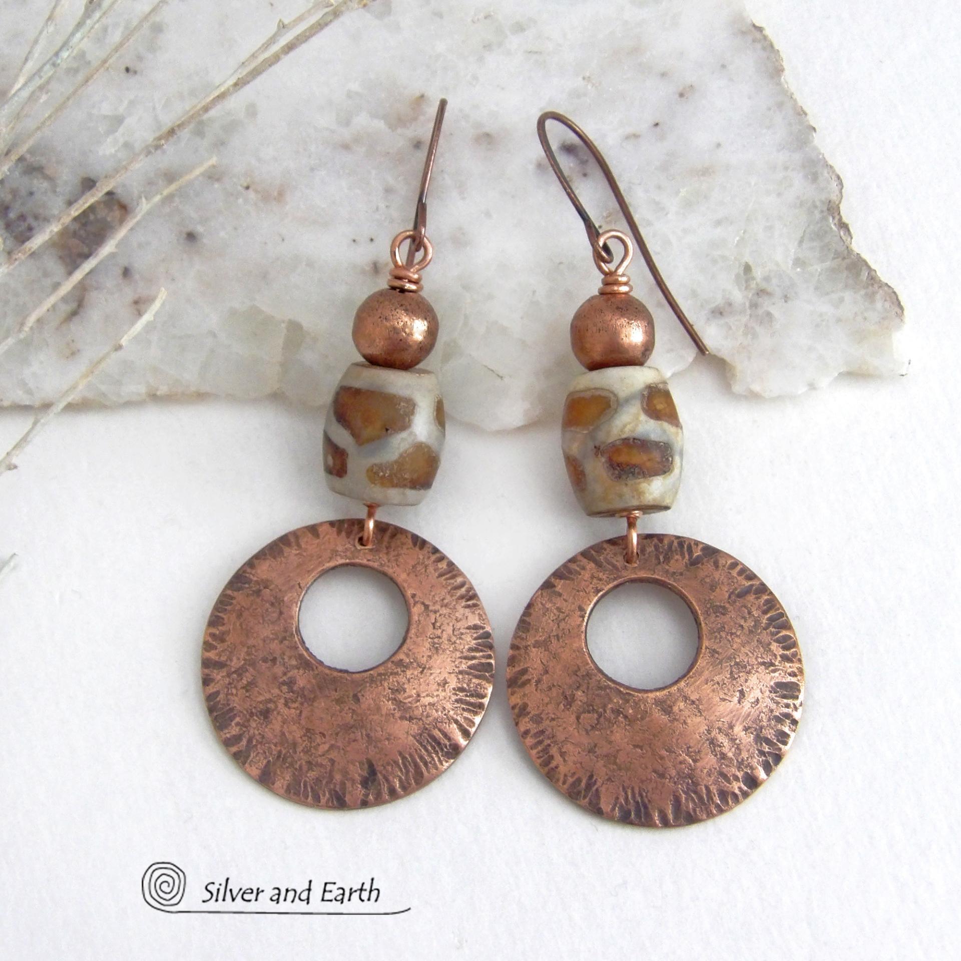 These handcrafted copper earrings have a bold, ethnic African style and flair. They feature round copper dangles with a rustic hammered texture accented with African etched giraffe print agate stones topped off with solid copper beads. Unique and striking, they'll make a bold statement. Perfect for women that love ethnic tribal style jewelry. Your choice of ear wire - copper or hypoallergenic niobium.