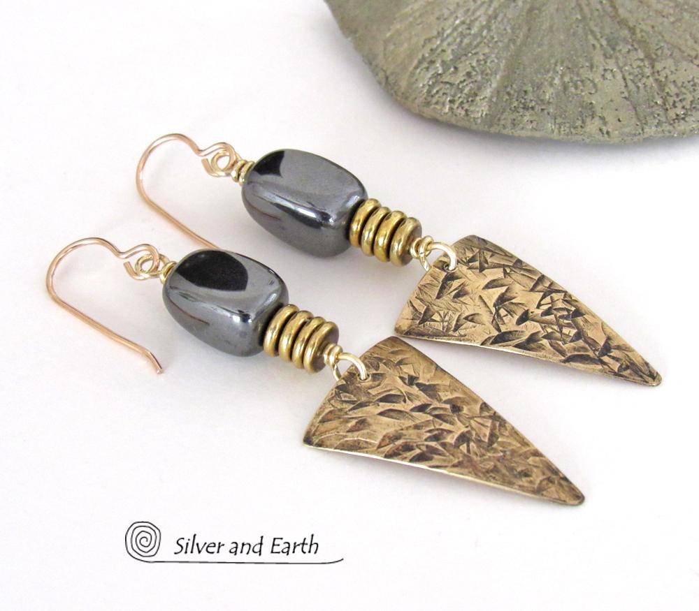 These gold brass triangle earrings have a hand stamped texture and are accented with natural hematite nugget-shaped gemstones on top of a stack of tiny brass beads. They have a modern contemporary and edgy style that makes a bold statement.