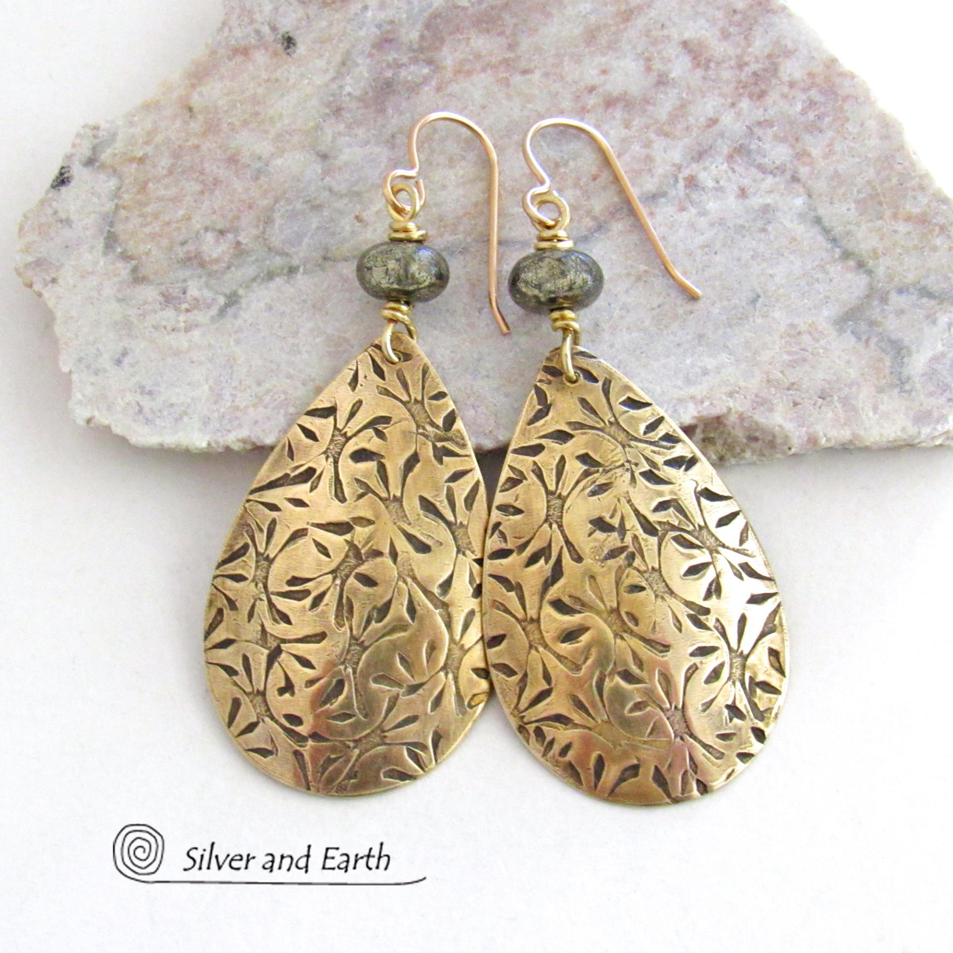 These handcrafted gold brass teardrop earrings have a hand stamped texture and are accented with natural silver pyrite gemstone beads. They have a modern contemporary style that coordinates beautifully with all wardrobe types.  MEASUREMENTS: Total length: 2-3/8” from top of bronze ear wires and 1” at widest point. Created out of solid gold brass; the shapes were hand stamped for texture; oxidized to enhance the detail. Handmade in the USA by Silver and Earth Jewelry.