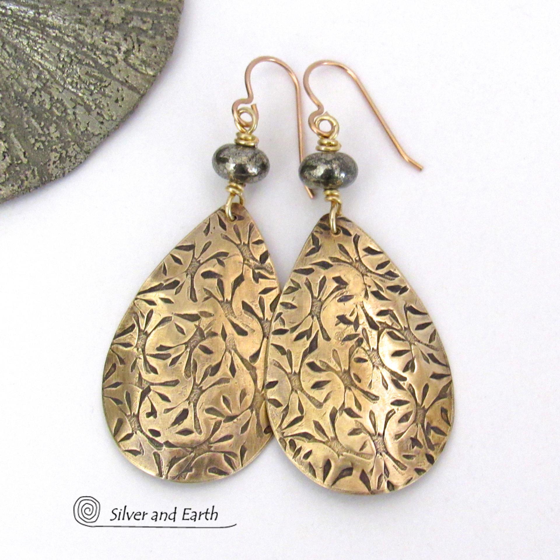 These handcrafted gold brass teardrop earrings have a hand stamped texture and are accented with natural silver pyrite gemstone beads. They have a modern contemporary style that coordinates beautifully with all wardrobe types.  MEASUREMENTS: Total length: 2-3/8” from top of bronze ear wires and 1” at widest point. Created out of solid gold brass; the shapes were hand stamped for texture; oxidized to enhance the detail. Handmade in the USA by Silver and Earth Jewelry.