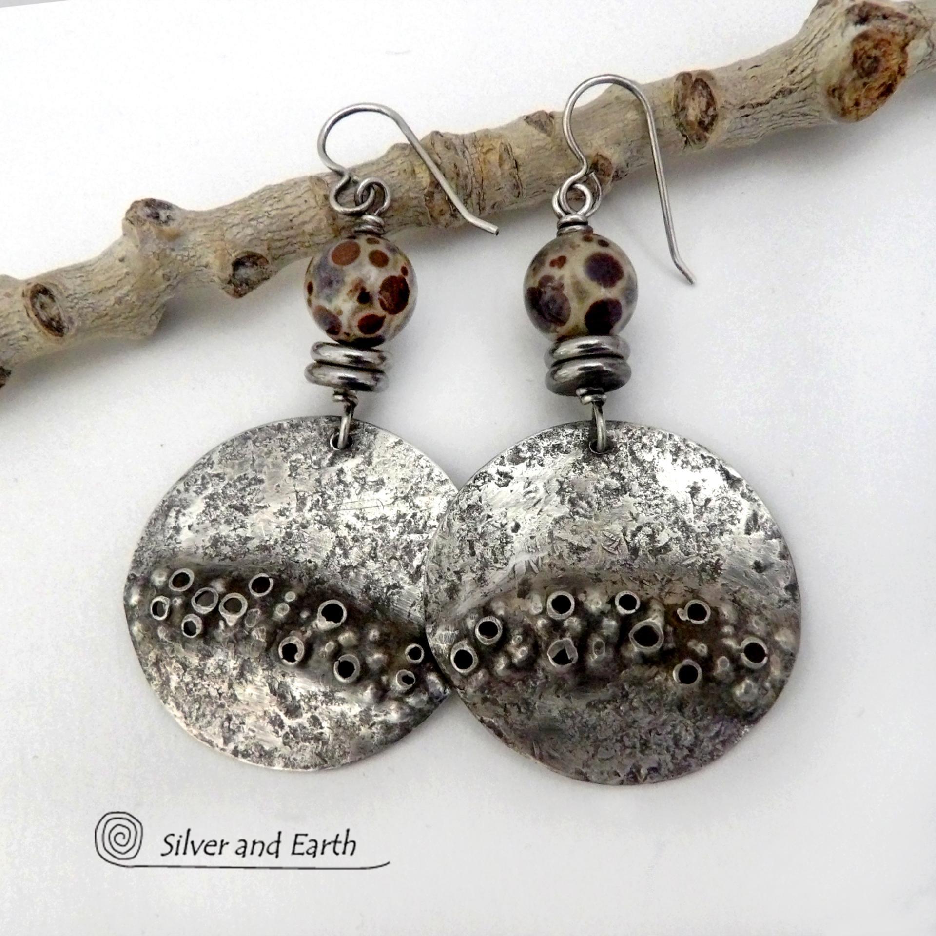 Unique and one-of-a-kind, these handcrafted large sterling silver earrings have a bold edgy vibe. They feature rustic hammered sterling silver accented with natural asteroid jasper stones and stainless steel beads. This type of stone is known for its unique dotted matrix in earth-tone hues of brown, gray and tan. It's also known as chocolate ocean jasper because it's found on the shores of Madagascar where ocean jasper is also found. Bold and striking - they're sure to make a unique statement.