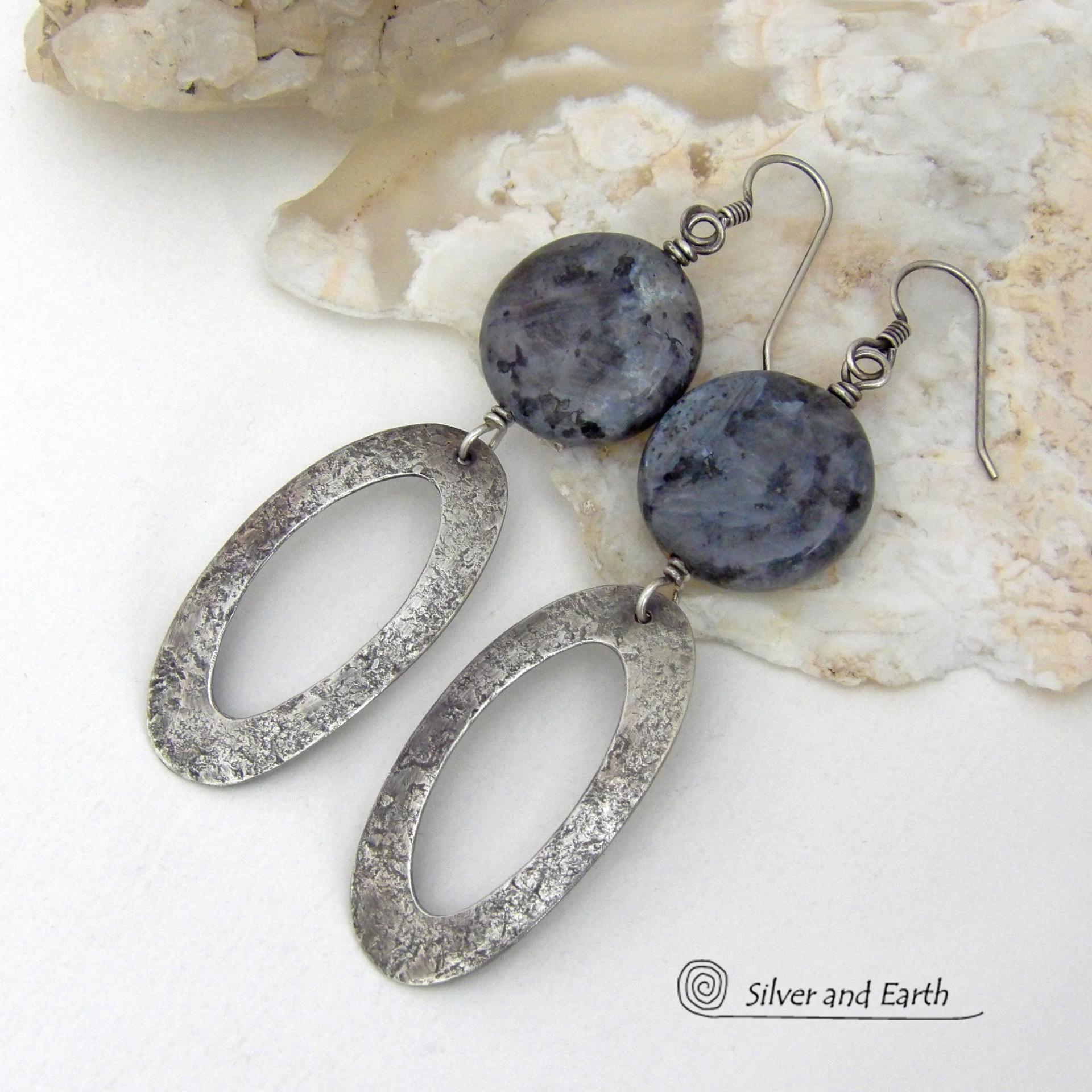 Modern, earthy & chic - these earrings feature big round natural larvikite gemstones accented with long sterling silver hoop dangles. The stones have a pearly, grayish black hue - along with blue iridescent flashes of light which cast off a natural shimmer & shine. They have a modern, contemporary style that coordinates beautifully with all wardrobe types. Larvikite originates from the Larvik region in Norway and is also called Norwegian moonstone and black labradorite. 