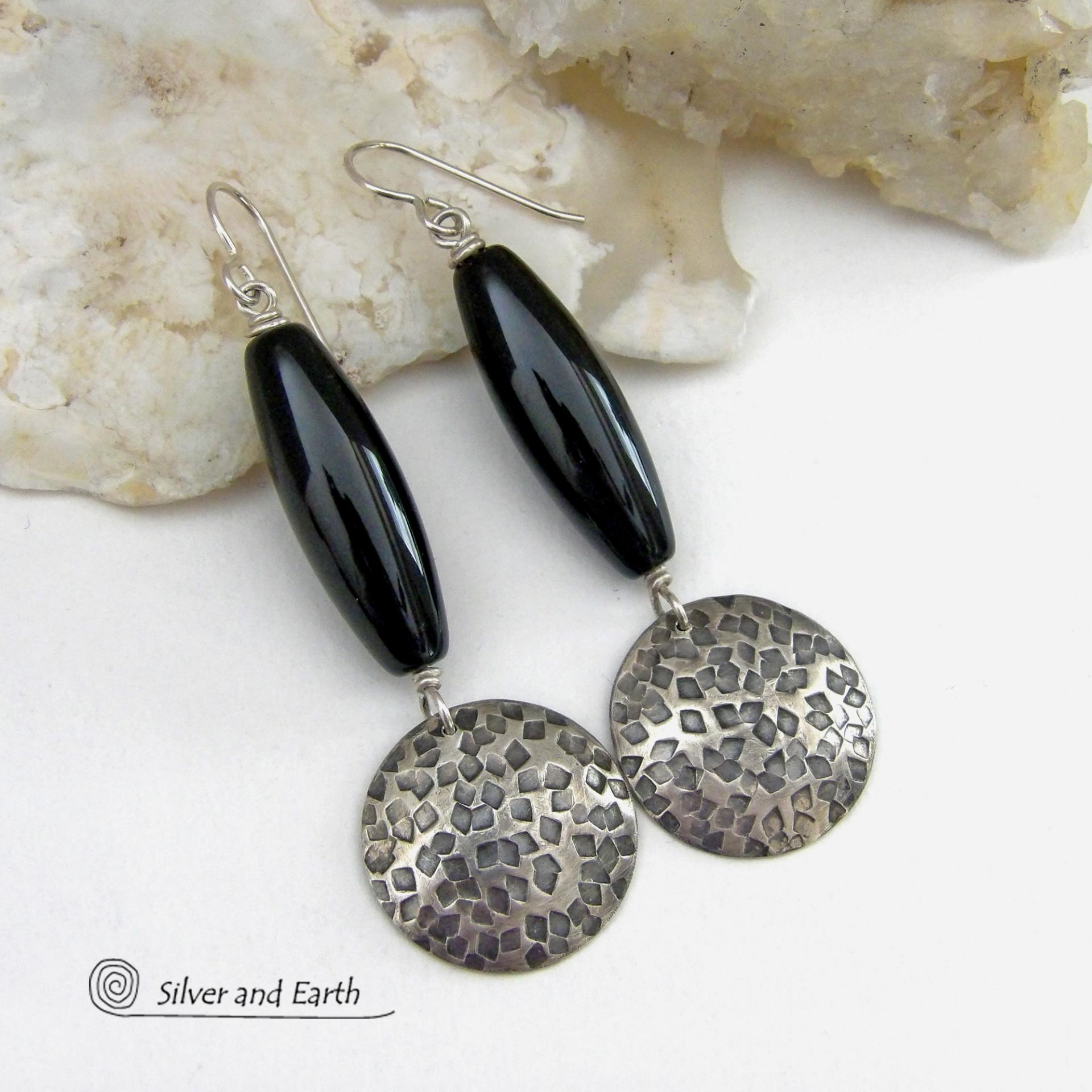 These handcrafted sterling silver dangle earrings have a hand stamped texture and oxidized finish and feature long black onyx gemstones. The stones are cut into a unique, elongated tubular shape and have a rich black hue and high polish. They have a modern, contemporary style that will look great with all wardrobe types. 