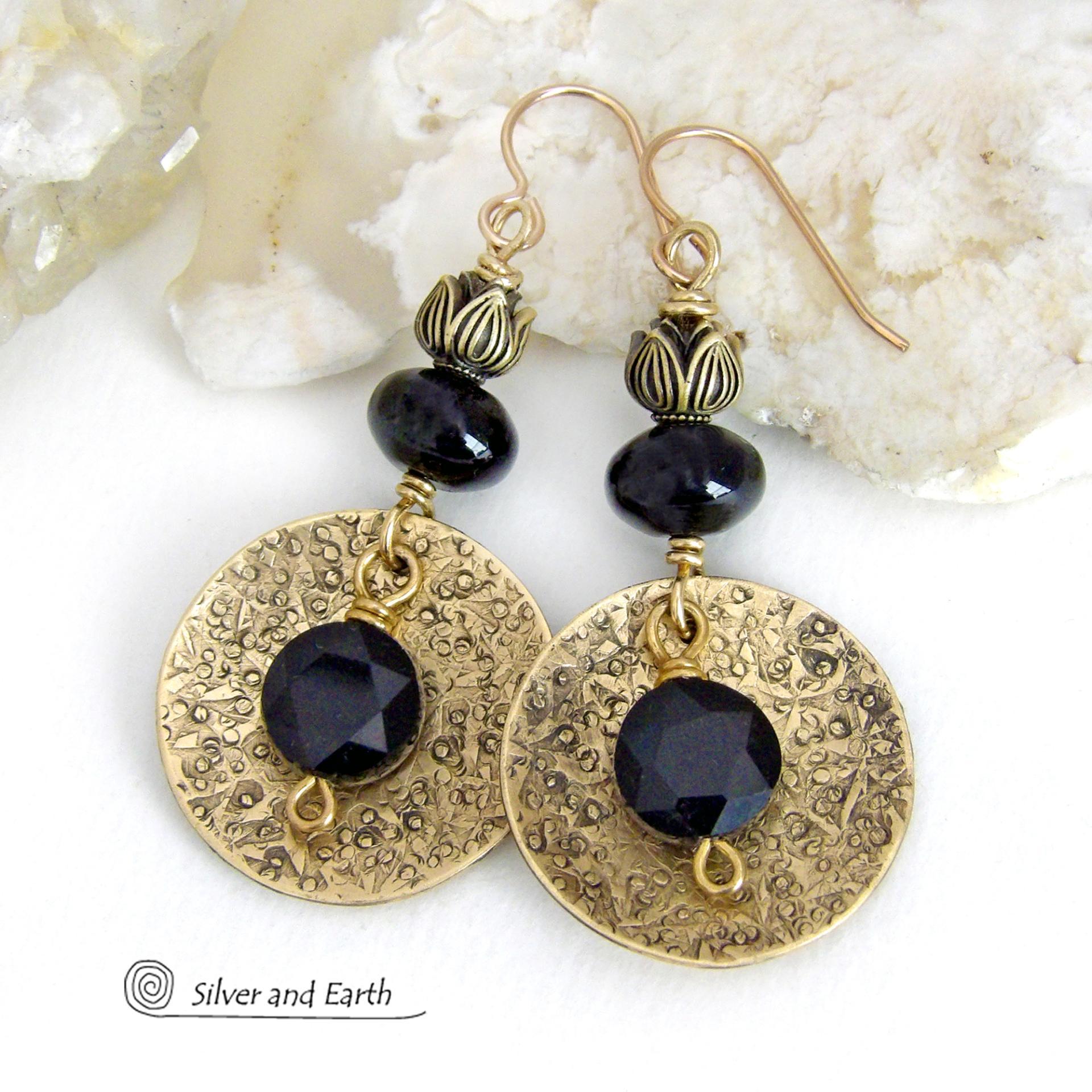 These handcrafted earrings feature gold brass dangles with a hand stamped texture accented with round black onyx gemstones dangling in front and topped off with black onyx gemstones and tulip flower-shaped beads. The round onyx stones have a faceted cut which casts off a beautiful natural sparkle and shine. They have a modern, elegant chic style that looks great dressed up or down. Perfect for women that love bold unique artisan handcrafted jewelry. Handmade in the USA by Silver and Earth Jewelry.