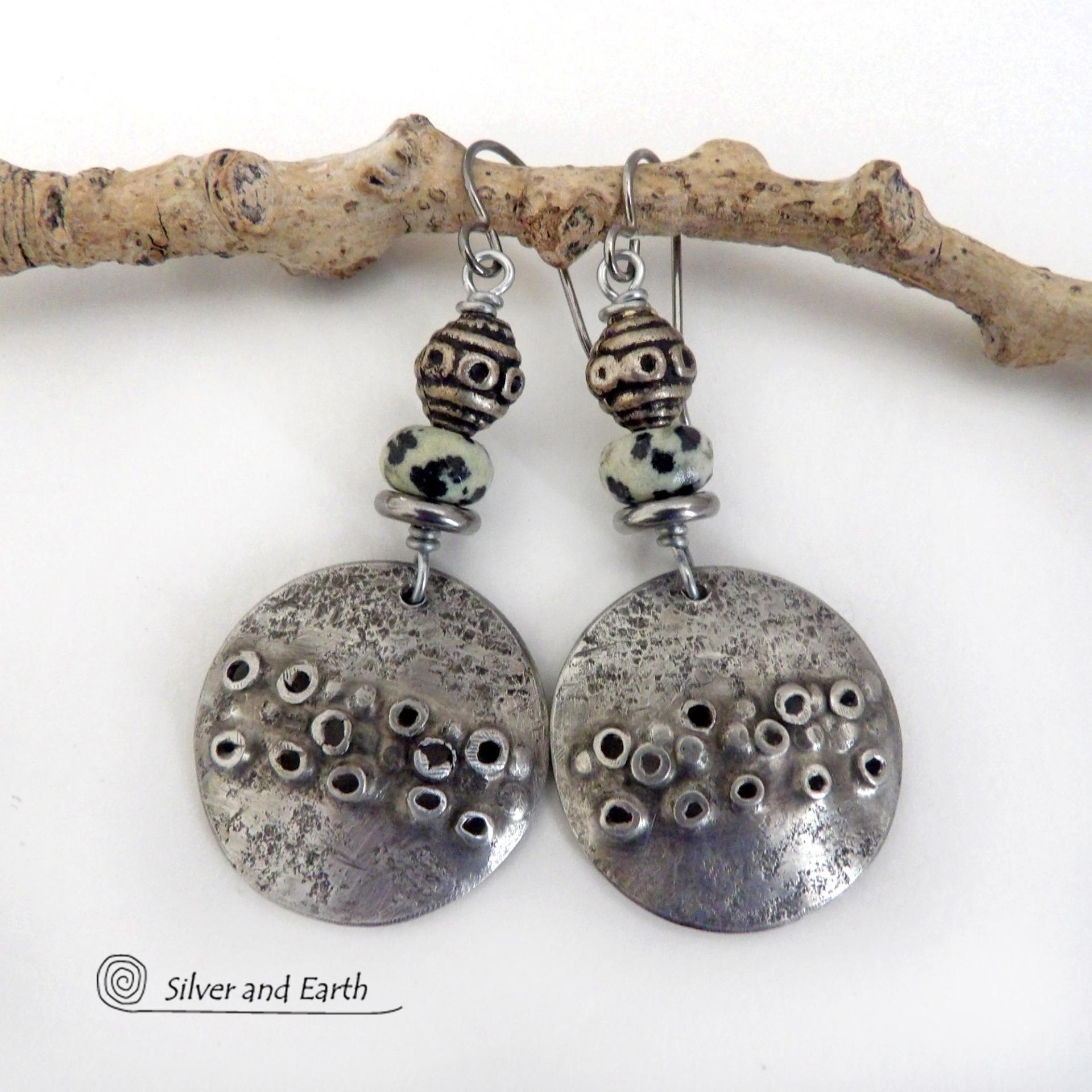 These handcrafted silver pewter earrings have a rustic, hand textured design and are accented with natural dalmatian jasper gemstones, stainless steel and vintage silver tone metal beads. They have an earthy, edgy organic style that makes a unique statement.This type of jasper is known for its spotted pattern that resembles the Dalmatian breed of dog. The matrix consists of mineral inclusions of brown iron oxide, black tourmaline & other minerals which create the natural "spots" in the stone. Handmade in th