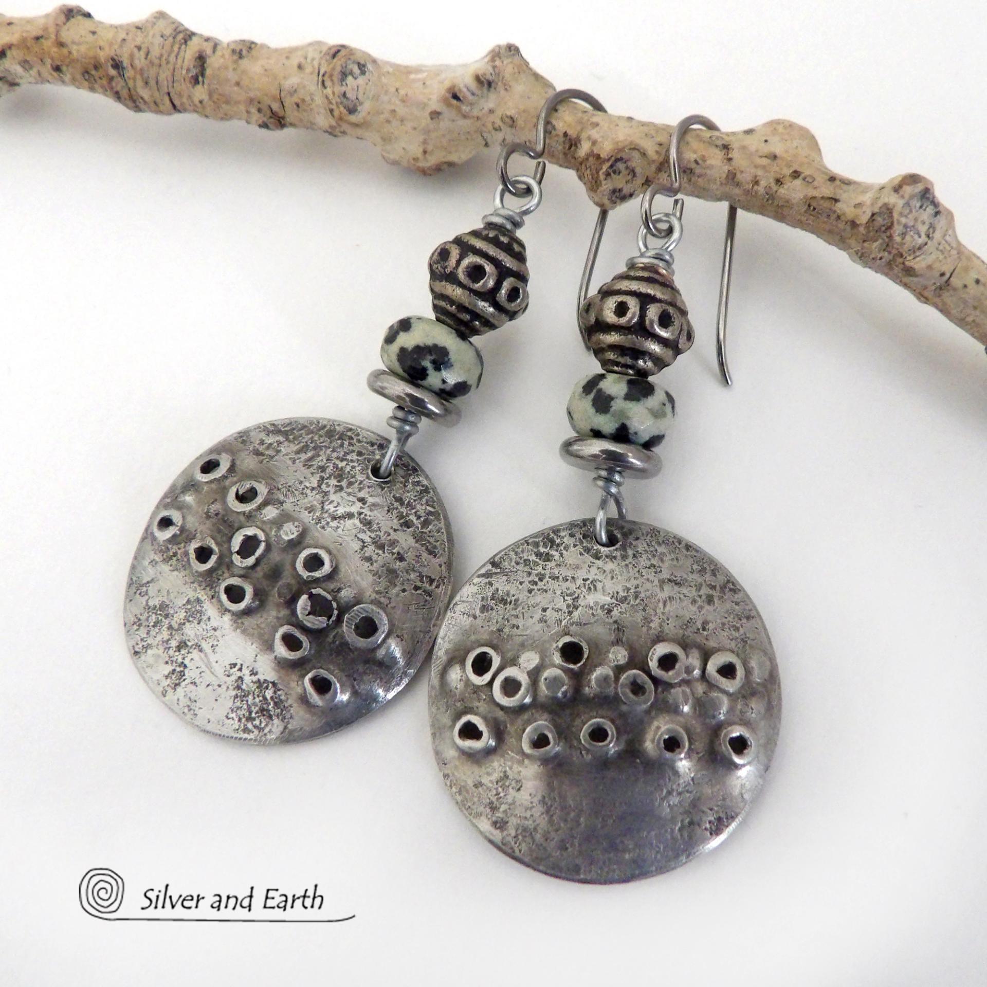 These handcrafted silver pewter earrings have a rustic, hand textured design and are accented with natural dalmatian jasper gemstones, stainless steel and vintage silver tone metal beads. They have an earthy, edgy organic style that makes a unique statement.This type of jasper is known for its spotted pattern that resembles the Dalmatian breed of dog. The matrix consists of mineral inclusions of brown iron oxide, black tourmaline & other minerals which create the natural "spots" in the stone. Handmade in th