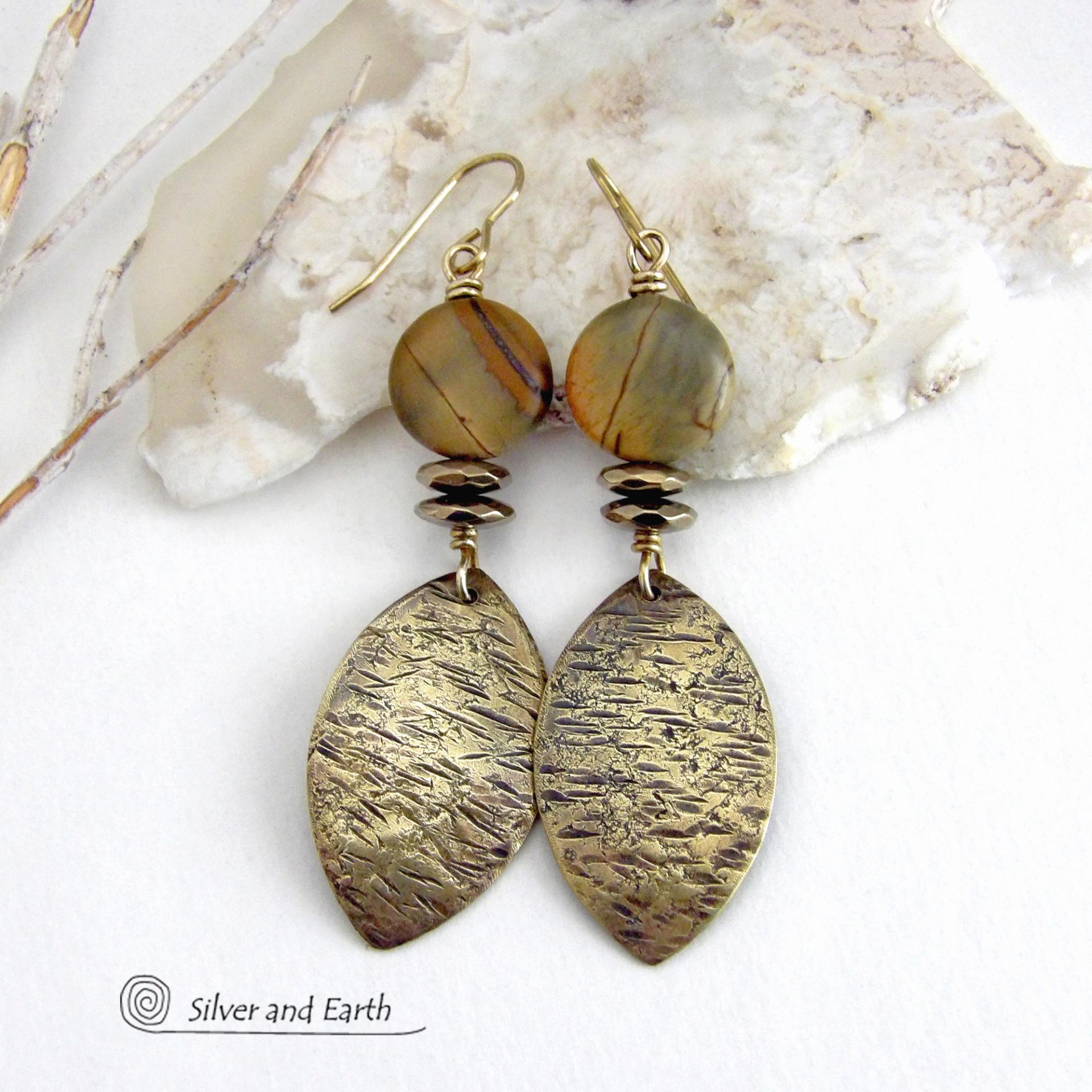 These handcrafted earrings feature textured gold brass dangles accented with natural Picasso jasper gemstones and hematite stone beads. The beads have an electroplated champagne gold tone finish which adds a touch of shimmer and shine. They have an earthy modern style that coordinates well with all wardrobe styles. Coordinating necklace is available and sold separately.