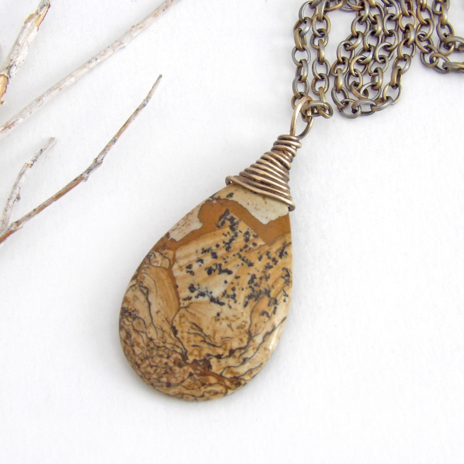 This one-of-a-kind necklace features a natural picture jasper stone wrapped in gold brass wire. The stone has an interesting matrix pattern with earthy hues of brown, tan and black. It has an earthy, simple style that coordinates beautifully with all wardrobe styles. It makes a great gift for a natural stone lover - or a nice addition to your own jewelry collection. Handmade in the USA by Silver and Earth Jewelry. Coordinating earrings sold separately.
