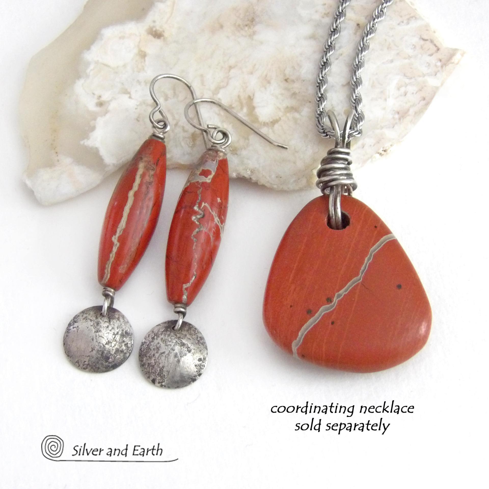 These handmade earrings feature natural red jasper gemstones accented with small hammered sterling silver dangles. The stones have a brick red hue with an interesting matrix of beige streaks and squiggly lines. They have a modern, earthy appeal that coordinates well with all wardrobe styles. They'll make a great gift for a natural stone lover - or a nice addition to your own jewelry wardrobe. They have a coordinating necklace which is sold separately. Handmade in the USA by Silver and Earth Jewelry.  
