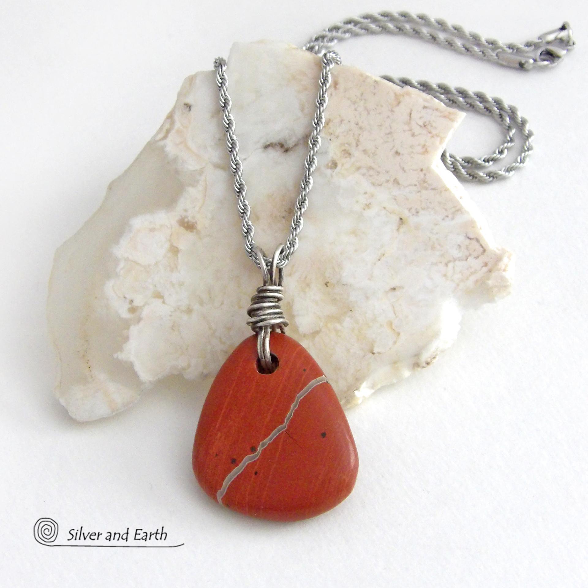 Simple and earthy - this pendant necklace features a natural red jasper gemstone with a wire wrapped sterling silver bail. The stone has a brick red hue with a natural matrix of beige streaks and dots. It has a modern minimalist appeal and is perfect for those that prefer simple, earthy jewelry that coordinates well with all wardrobe styles. It makes a great gift for a natural stone lover - or a nice addition to your own jewelry wardrobe. Handmade in the USA by Silver and Earth Jewelry. 