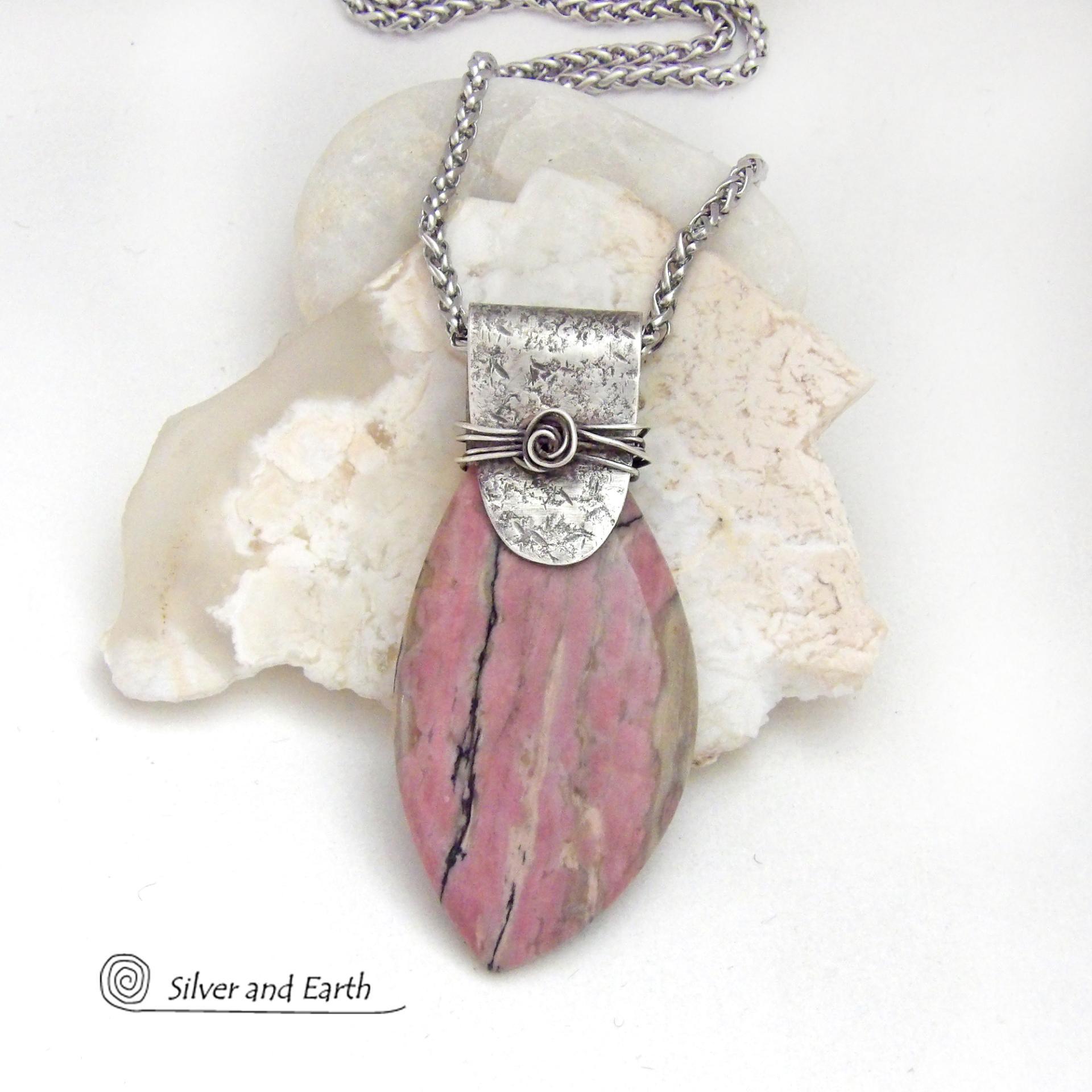 This one-of-a-kind necklace features a large gorgeous rhodonite gemstone accented with a handcrafted sterling silver bail. The stone has a beautiful pink hue with a natural matrix pattern of black, white and tan lines. Coordinating earrings sold separately. Makes a great gift for a natural stone lover - or a nice addition to 