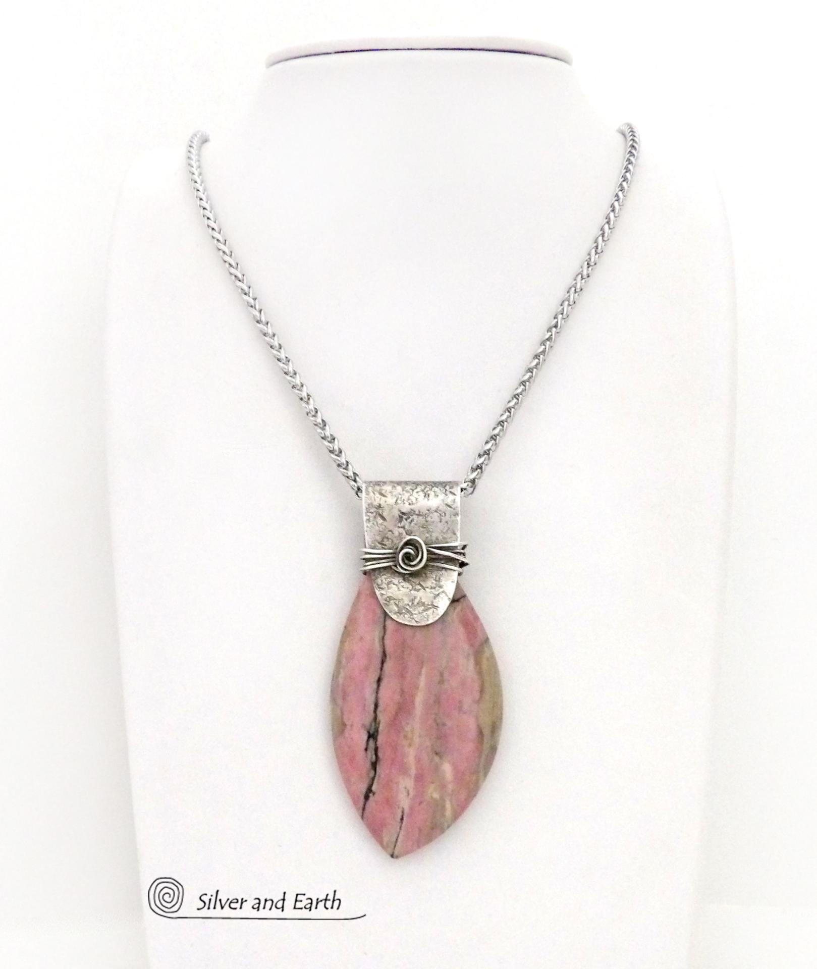 This one-of-a-kind necklace features a large gorgeous rhodonite gemstone accented with a handcrafted sterling silver bail. The stone has a beautiful pink hue with a natural matrix pattern of black, white and tan lines. Coordinating earrings sold separately. Makes a great gift for a natural stone lover - or a nice addition to 