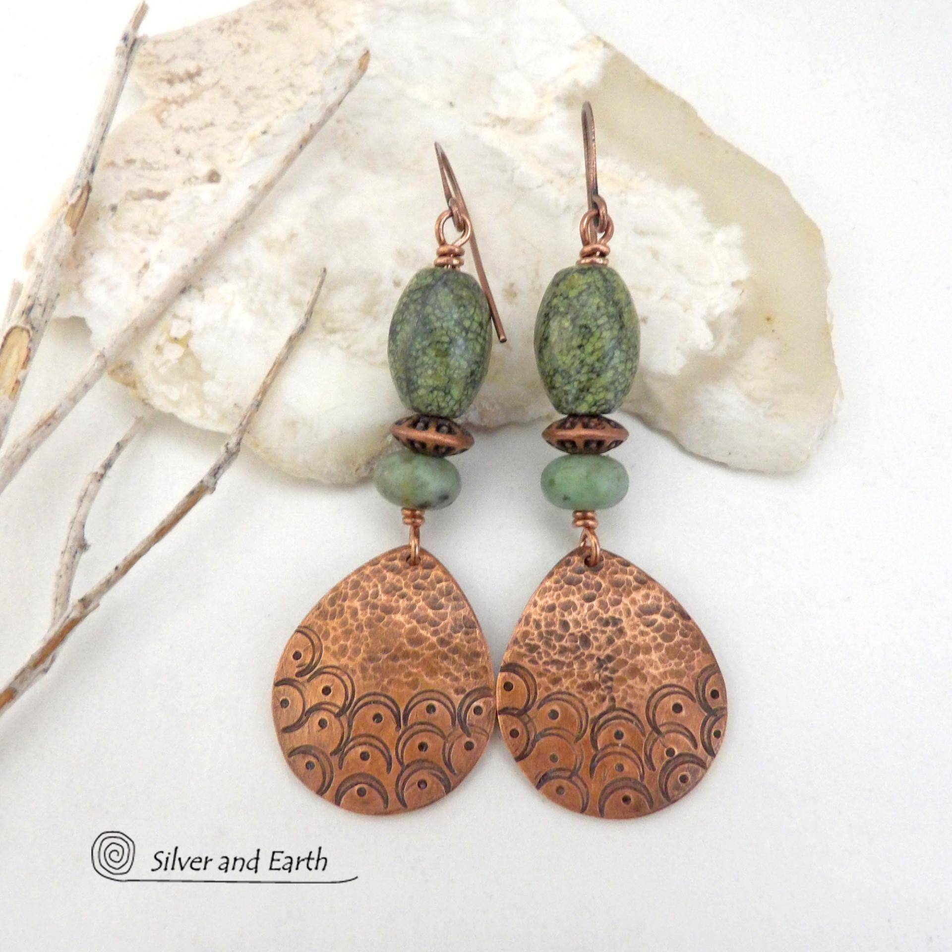 These handcrafted copper earrings have a hammered and hand stamped texture and are accented with green Russian serpentine stones. Russian serpentine is known for its unique natural patterns with light and dark green speckles and web-like patterns. They are accented with small, light green African turquoise stones and copper beads. Bold and unique, they have a boho chic flair and will make a striking statement. Handmade in the USA by Silver and Earth Jewelry.