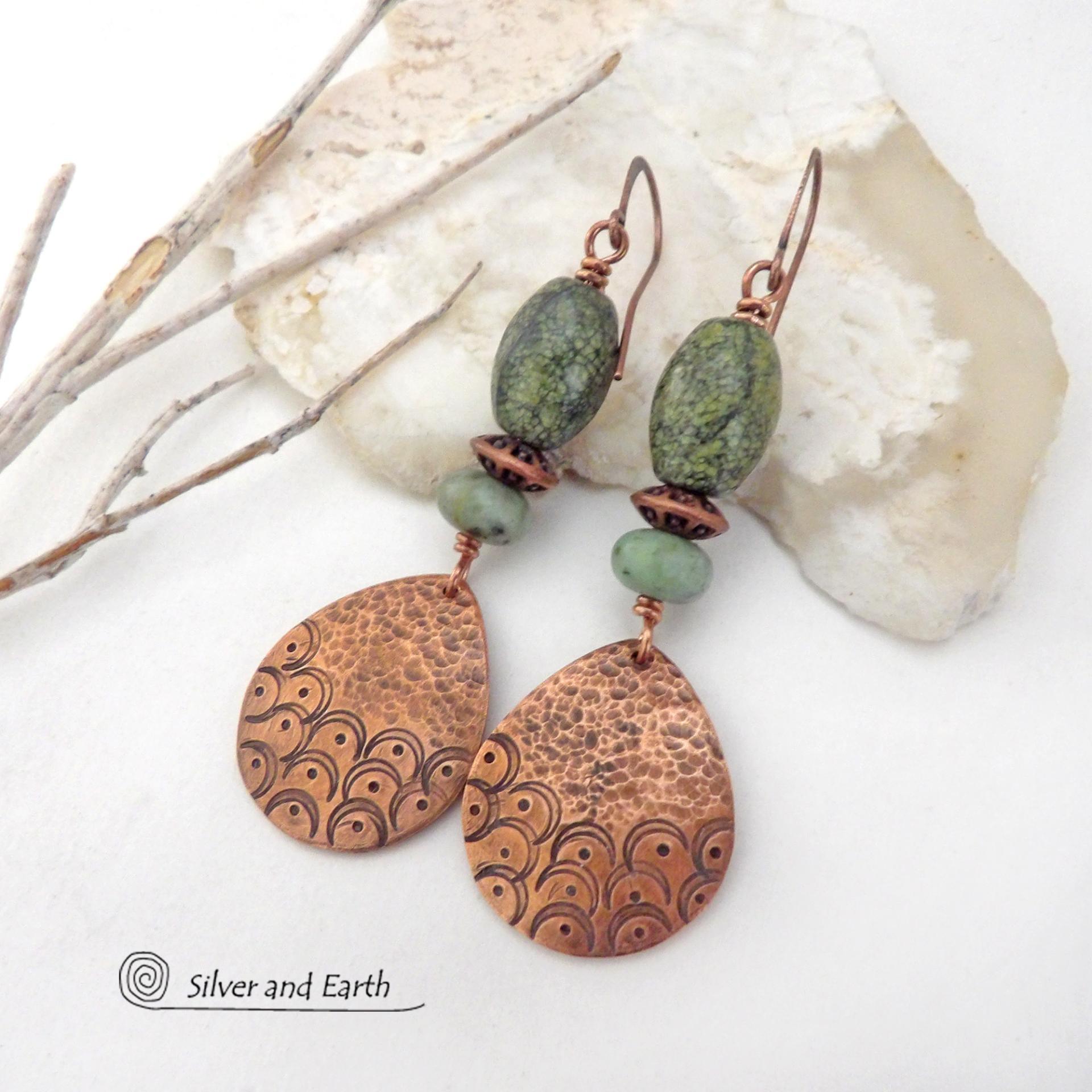 These handcrafted copper earrings have a hammered and hand stamped texture and are accented with green Russian serpentine stones. Russian serpentine is known for its unique natural patterns with light and dark green speckles and web-like patterns. They are accented with small, light green African turquoise stones and copper beads. Bold and unique, they have a boho chic flair and will make a striking statement. Handmade in the USA by Silver and Earth Jewelry.