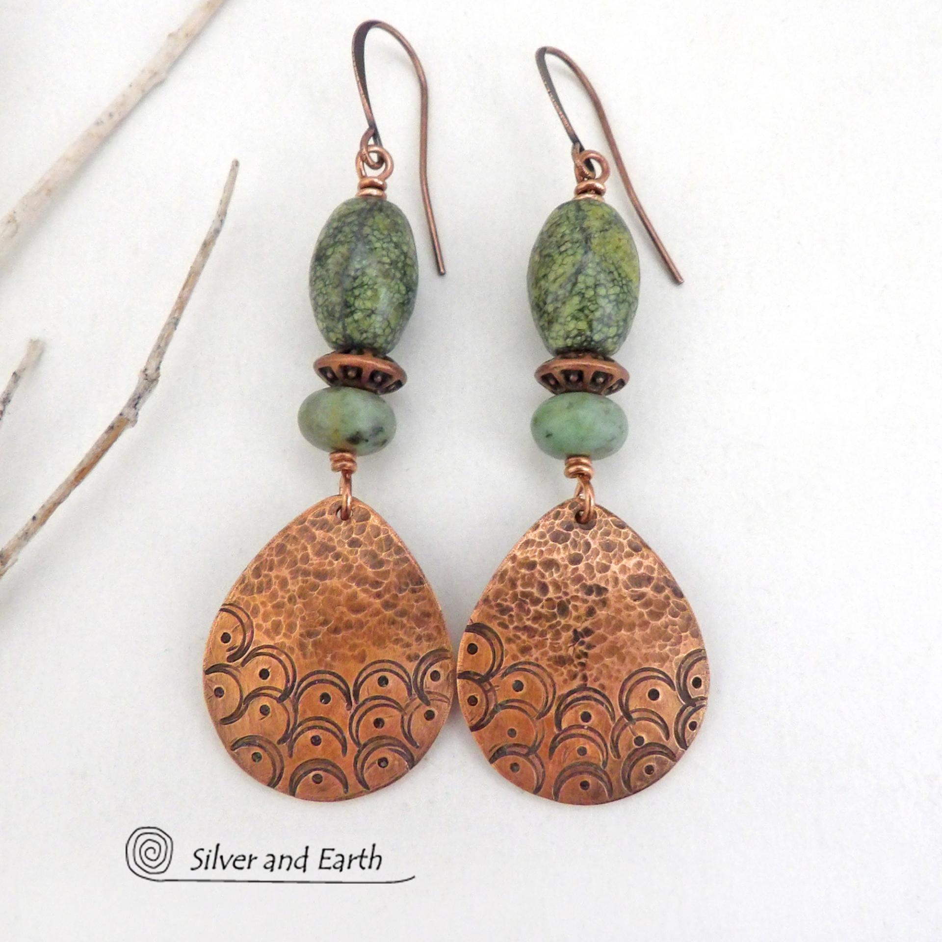 These handcrafted copper earrings have a hammered and hand stamped texture and are accented with green Russian serpentine stones. Russian serpentine is known for its unique natural patterns with light and dark green speckles and web-like patterns. They are accented with small, light green African turquoise stones and copper beads. Bold and unique, they have a boho chic flair and will make a striking statement. Handmade in the USA by Silver and Earth Jewelry.