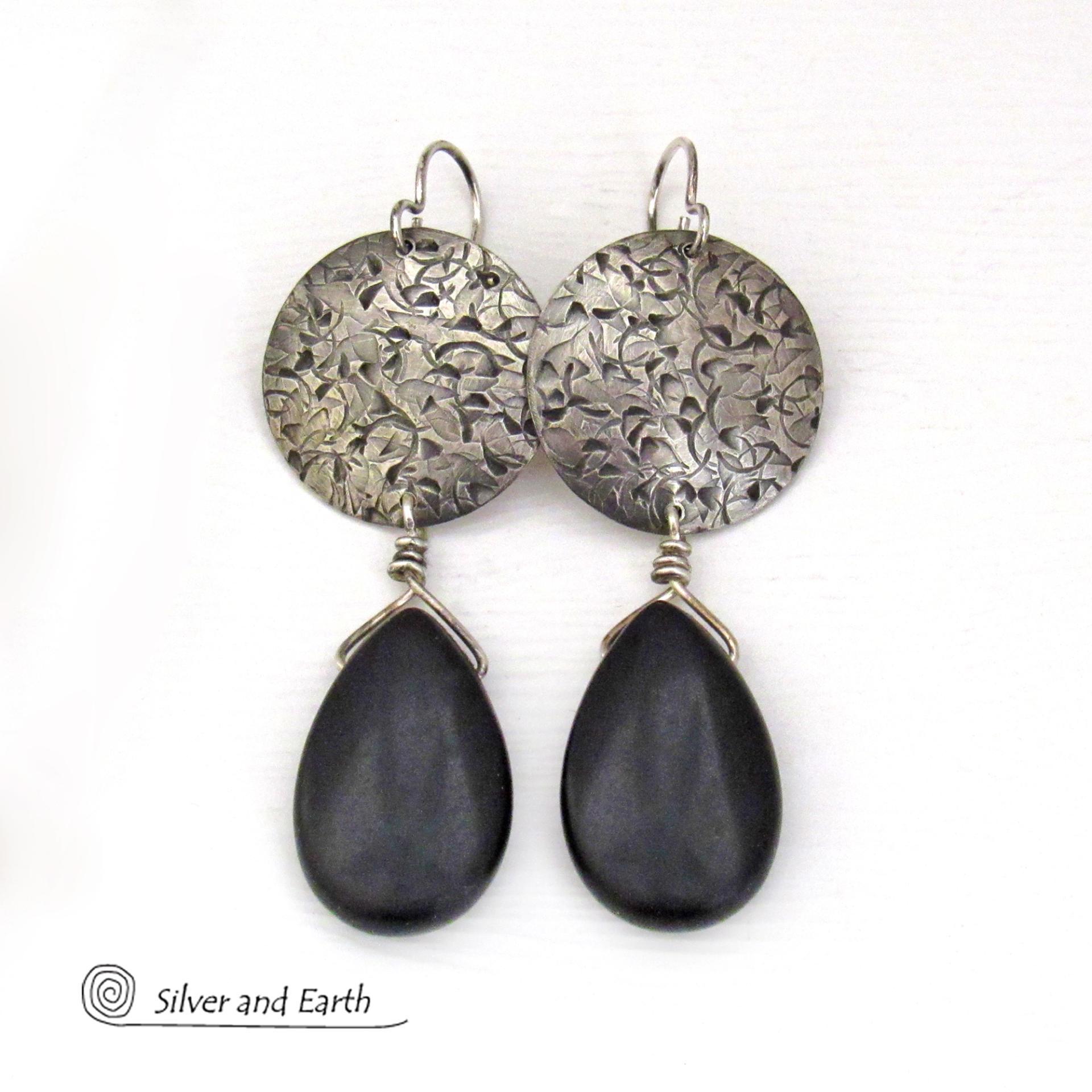 These handcrafted sterling silver earrings have a hand stamped texture and feature dangling black onyx teardrop-shaped gemstones. They have a contemporary modern style with a bold urban chic flair that coordinates beautifully with all wardrobe types.
