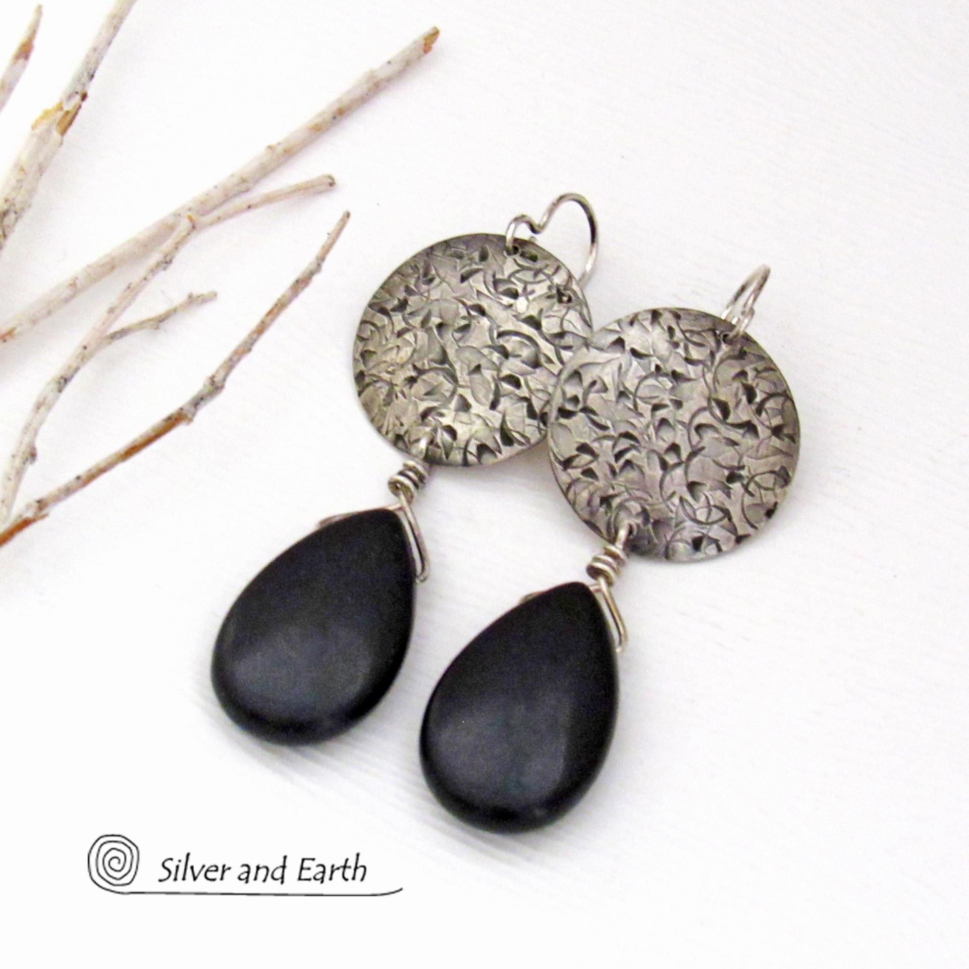 These handcrafted sterling silver earrings have a hand stamped texture and feature dangling black onyx teardrop-shaped gemstones. They have a contemporary modern style with a bold urban chic flair that coordinates beautifully with all wardrobe types.