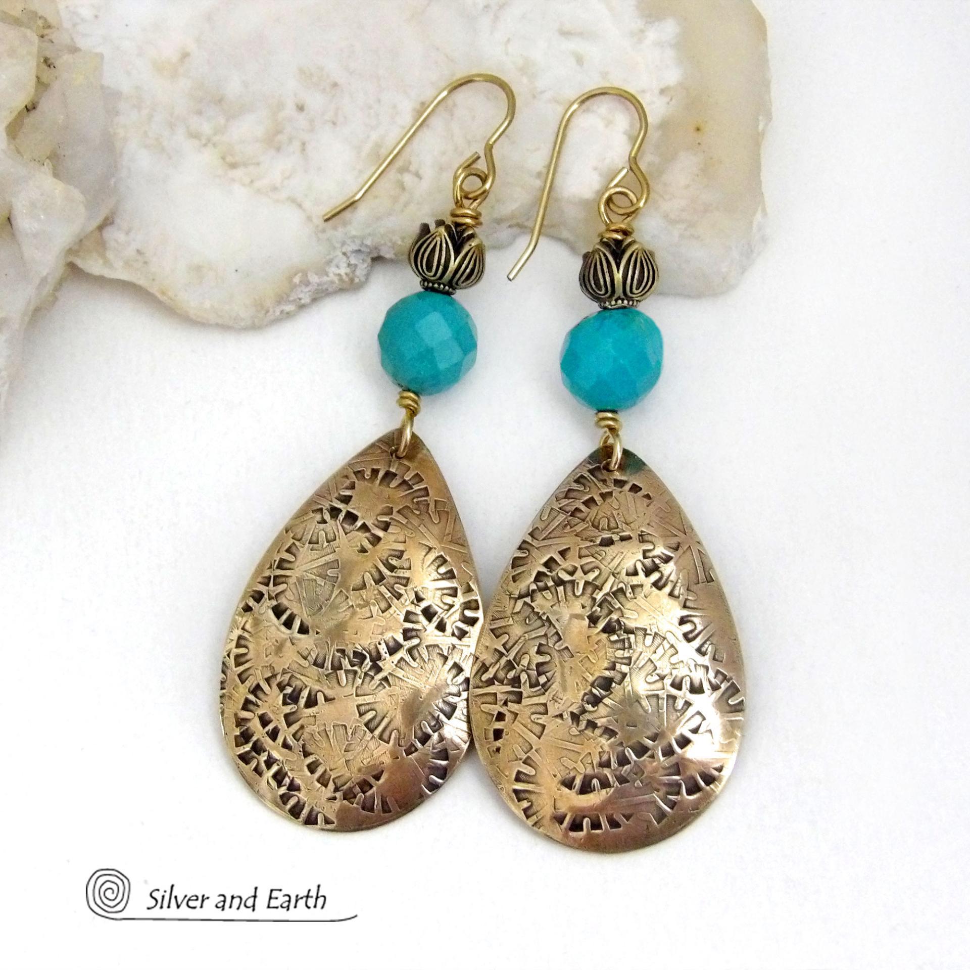 These handcrafted gold brass teardrop dangle earrings have a hand stamped texture accented with natural turquoise gemstones with a faceted finish and tulip flower-shaped brass beads. Big, long and striking - they have a modern elegant boho chic style that makes a bold statement. They'll coordinate beautifully with all wardrobe types - dressed up or down. Handmade in the USA by Silver and Earth Jewelry. 