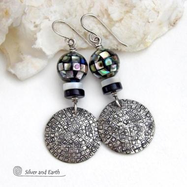These handcrafted sterling silver earrings feature an abstract hand stamped texture and are accented with inlaid abalone shell mosaic, black onyx and mother-of-pearl beads. The abalone beads resemble disco balls and have a beautiful rainbow iridescence of various colors. Bold and unique, they have a modern contemporary style and will make a striking statement. Handmade in the USA by Silver and Earth Jewelry. Length: approx. 2-1/8” from top of sterling silver ear wires and 7/8". 