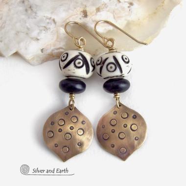 These handcrafted gold brass earrings have an ethnic, boho tribal vibe that makes a unique bold statement. They feature brass drops with a hand stamped texture accented with African carved bone beads with a bold pattern of dots and lines and matte black glass beads. Perfect for women that love unique handmade jewelry. Handmade in the USA by Silver and Earth Jewelry.