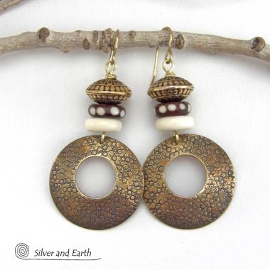 Big and bold, these handcrafted gold brass hoop earrings have a hand stamped texture and are accented with African batik bone dark brown beads with a dotted pattern, off-white bone beads and textured gold brass beads. They have an exotic ethnic and boho chic vibe that makes a striking, unique statement. Handmade in the USA by Silver and Earth Jewelry.