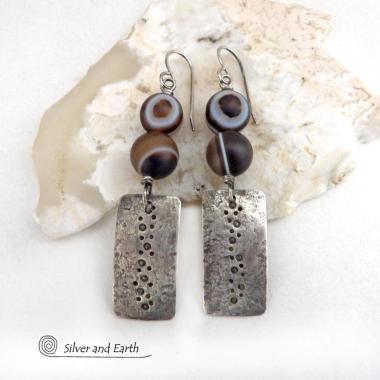 These handcrafted sterling silver earrings feature sterling silver rectangles with a hammered and hand stamped texture accented with natural Botswana agate gemstones. The stones have a smoky brown hue with a natural orbicular "eye" and line pattern. Botswana agate is a unique, banded chalcedony from Southern Africa. Bold and unique, these earrings are one-of-a-kind and will make a striking statement. Handmade in the USA by Silver and Earth Jewelry. 