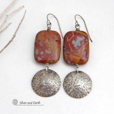 These one-of-a-kind handcrafted earrings feature natural Noreena jasper gemstones accented with textured sterling silver dangles. This stone is known for its dramatic abstract and geometric patterns and is found only in the Pilbara region of Western Australia. The stones in this pair have a great pattern consisting of hues of deep burgundy-red with fiery orange and gray streaks. 
