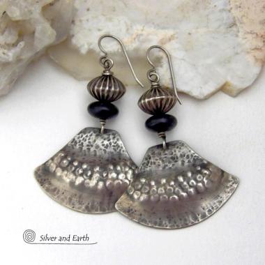 These handcrafted sterling silver earrings have a modern southwestern flair. The sterling shapes have a hammered and stamped texture with an oxidized finish. They are accented with Native Navajo pearl style oxidized sterling silver beads with a rich, corrugated texture and matte black glass beads. Unique and striking, they'll make a bold statement. Handmade in the USA by Silver and Earth Jewelry.